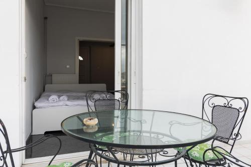 a glass table and chairs on a balcony with a bed at An adorable Apartment in Athens in Athens