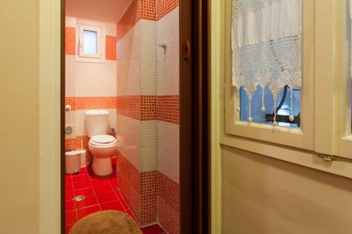 Baño pequeño con aseo y azulejos rojos en Psyri Neoclassical House with Yard, en Atenas