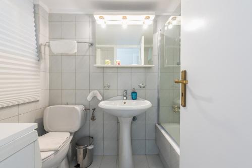 ein weißes Bad mit einem Waschbecken und einem WC in der Unterkunft Cozy and fresh apt close to Metro in Athen