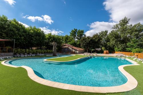 - une piscine dans une cour avec des chaises et des arbres dans l'établissement Camping maeva Escapades Millau Plage, à Millau