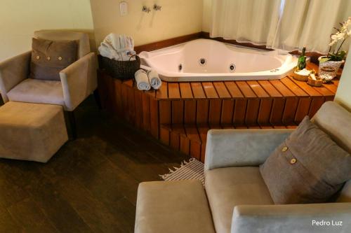 a bathroom with a tub and a chair and a couch at Pousada Villa Luna in Penedo