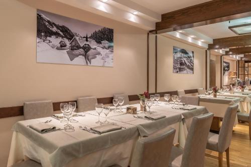 un gruppo di tavoli in una stanza con tovaglie bianche di Hotel Italo a Madonna di Campiglio