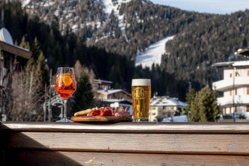 a table with a glass of beer and a plate of food at Hotel Italo in Madonna di Campiglio