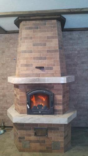 a brick fireplace with a fire in it at Синевирський Краєвид in Synevyr