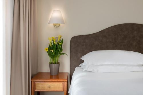 Un dormitorio con una cama y una mesa con un jarrón de flores en Hotel Adlon - FRONTE MARE, en Riccione