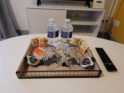 a tray with two bottles of water and spoons at Appartements entiers proche Aéroport - ZAC Chesnes - CNPE du Bugey Check-In 24h7J in Satolas-et-Bonce