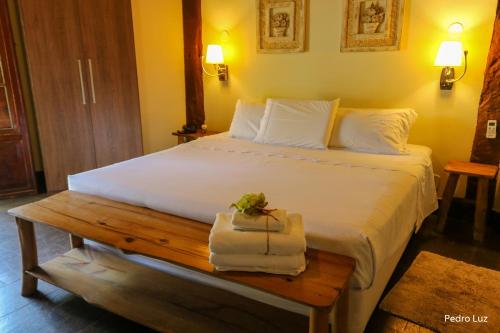 a bedroom with a bed and a table with a towel at Pousada Villa Luna in Penedo