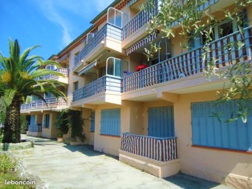 un grand bâtiment avec des balcons bleus et un palmier dans l'établissement studio climatisé et calme, proche centre et mer, à Mandelieu-la-Napoule