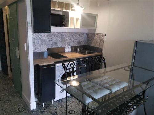 une petite cuisine avec une table en verre et une cuisinière dans l'établissement studio climatisé et calme, proche centre et mer, à Mandelieu-la-Napoule