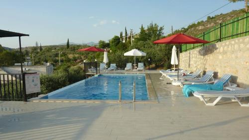 a swimming pool with lounge chairs and umbrellas at Hotel Sema in Patara