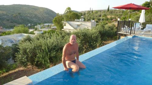 a man sitting on the edge of a swimming pool at Hotel Sema in Patara