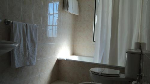 y baño con aseo y cortina de ducha. en Hotel Das Termas, en Monfortinho