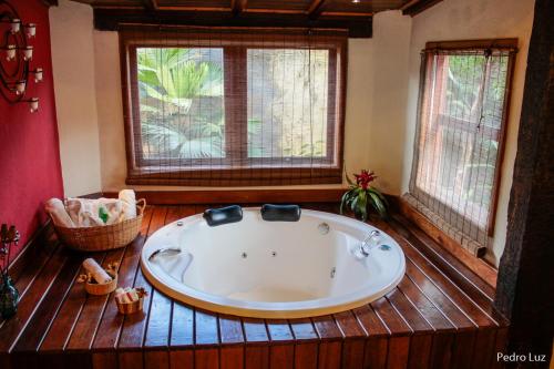 a large bath tub in a room with two windows at Pousada Villa Luna in Penedo