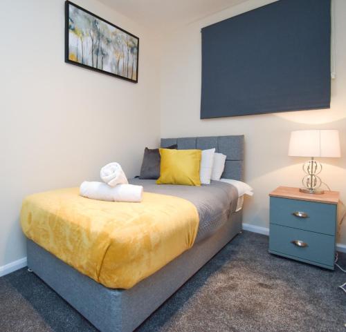 - une chambre avec un lit doté de draps jaunes et d'une lampe dans l'établissement Silicon Court -Milton Keynes -4 bedroom Sleeps 7, à Milton Keynes