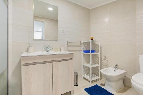 a white bathroom with a sink and a toilet at Maison de la Mer by Innkeeper in Sesimbra