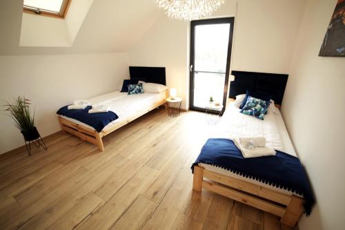 two beds in a room with wooden floors and a chandelier at New House Mazury in Sorkwity