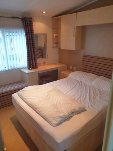 a bedroom with a large white bed and a kitchen at Barmouth Lyons Sunnysands 346 in Talybont