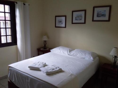 Un dormitorio con una cama blanca con toallas. en Seestern Gasthaus en Cananéia