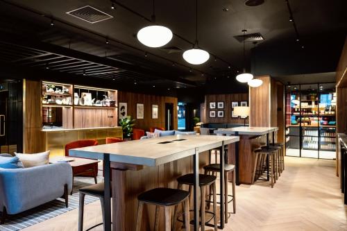 un bar con taburetes y mesas en un restaurante en Wilde Aparthotels London Paddington, en Londres