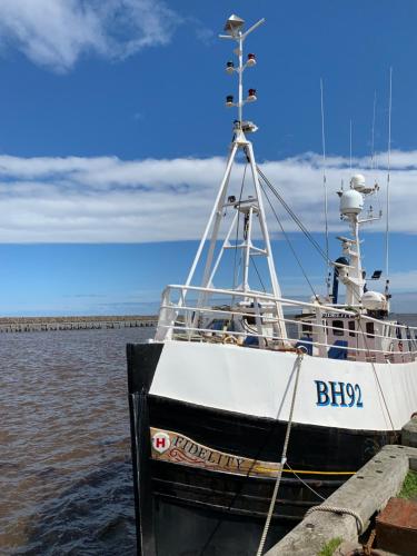 a boat tied up to a dock in the water at The Anchorage - sea views and beach on doorstep in Amble
