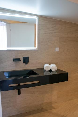 a bathroom with a black counter with two towels on it at 5ª Vigia in Porto de Mós
