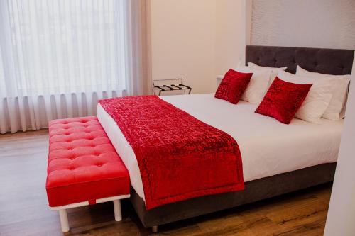 a bedroom with a bed with a red blanket and a red chair at 5ª Vigia in Porto de Mós