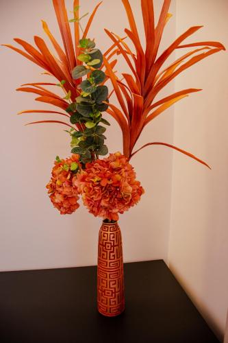 a vase with orange flowers in it on a table at 5ª Vigia in Porto de Mós