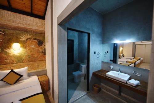 Zimmer mit einem Bad mit einem Waschbecken und einem Spiegel in der Unterkunft Ele Camp Udawalawe in Udawalawe