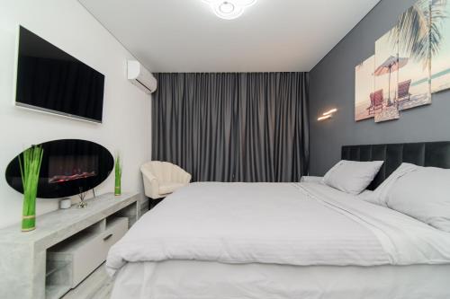 a bedroom with a white bed and a tv at Apartament Buiucani Alba Iulia in Chişinău