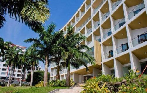 a large building with palm trees in front of it at MAKANA Tonsupa - Suites y Departamentos Familiares - Deluxe Suites in Tonsupa