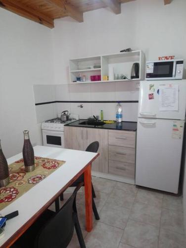 eine Küche mit einem Tisch und einem weißen Kühlschrank in der Unterkunft Departamento Udine in General Roca