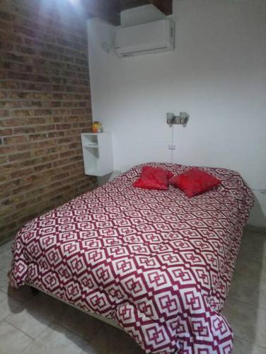 ein Schlafzimmer mit einem Bett mit roten Kissen darauf in der Unterkunft Departamento Udine in General Roca