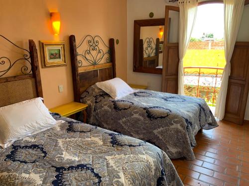 a bedroom with two beds and a window and a mirror at Casa Miguel Arcangel in Coatepec