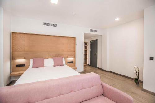 a bedroom with a large bed and a pink couch at Hotel Ciudad De Ávila in Avila