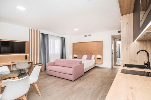 Habitación de hotel con cama y sofá rosa en Hotel Ciudad de Ávila en Ávila