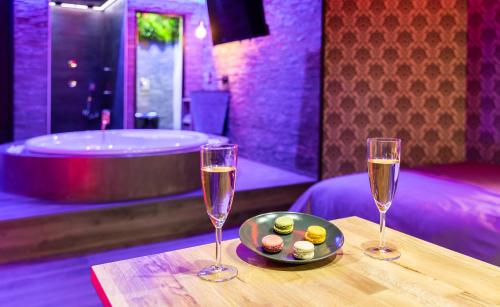 uma mesa com duas taças de champanhe e um prato de comida em Cupidon Love Room em Vesoul