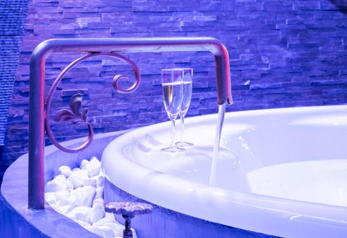 La salle de bains est pourvue d'une baignoire et d'une coupe de champagne. dans l'établissement Cupidon Love Room, à Vesoul