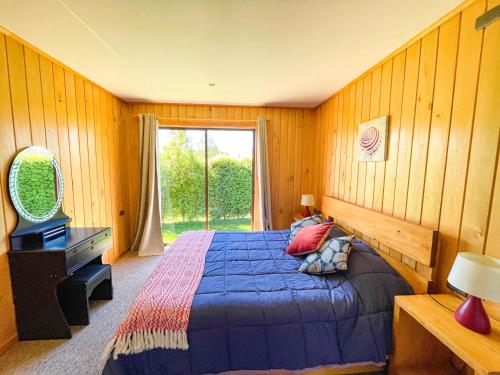 a bedroom with a blue bed and a window at Cabaña Ayekantun Futrono in Futrono