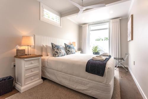 Un dormitorio blanco con una cama grande y una ventana en Hampton Court, en Oneroa