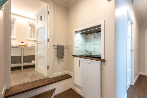 a kitchen with white cabinets and a sink at Hampton Court in Oneroa