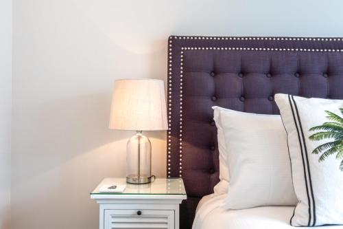 a bedroom with a bed with a lamp on a night stand at Hampton Court in Oneroa