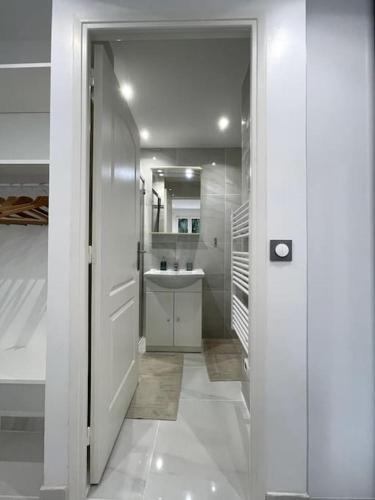 une salle de bain blanche avec un lavabo et un miroir dans l'établissement Appartement Cosy et Moderne proche de DISNEYLAND, à Bussy-Saint-Georges