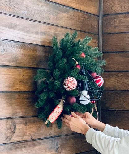 a person holding a christmas wreath on a wooden wall at Girske Povitria 2 in Yaremche