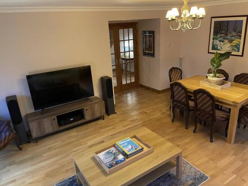 un soggiorno con TV e tavolo con sedie di Foxglove Cottages a Drymen