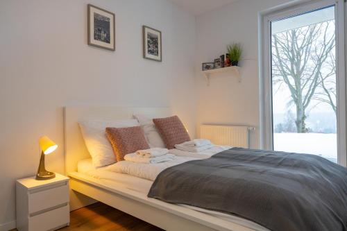 a white bedroom with a bed with a window at Karkonosky Apartamenty - Izery in Szklarska Poręba