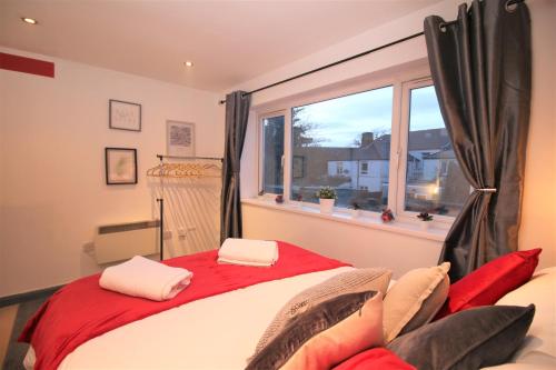 a bedroom with a red and white bed and a window at Northcote Lane Apartments by Property Promise in Cardiff