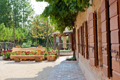 a wooden bench sitting next to a building with flowers at Ca' Muliner in Azzano Decimo