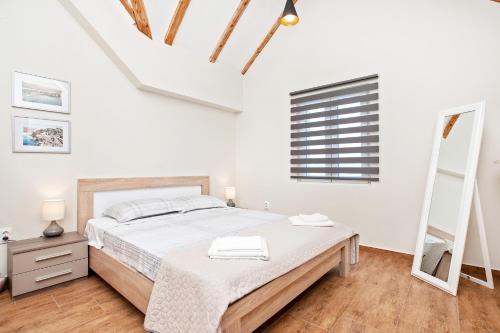 a white bedroom with a bed and a window at Apartments Isja in Tivat
