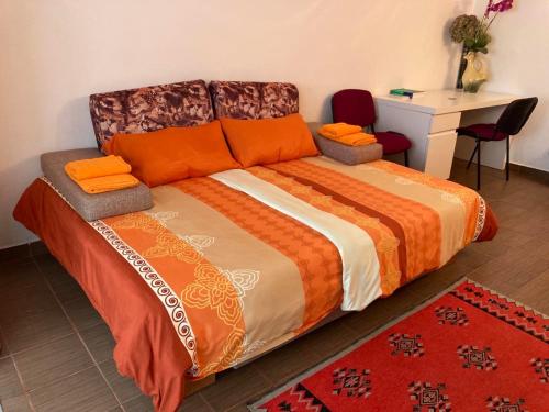 un letto con cuscini arancioni e una scrivania in camera di Apartament Bazyla a Truskavec'