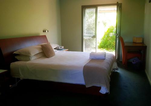 1 dormitorio con 1 cama blanca grande y ventana en Red Brier Cottage Accommodation, en Richmond